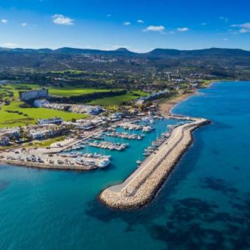 Latchi Aerial bird's eye view of Latchi port, Akamas peninsula, Polis Chrysochous, Paphos, Cyprus. The Latsi harbour with boats and yachts, fish restaurants, promenade, beach tourist area and mountains from above.